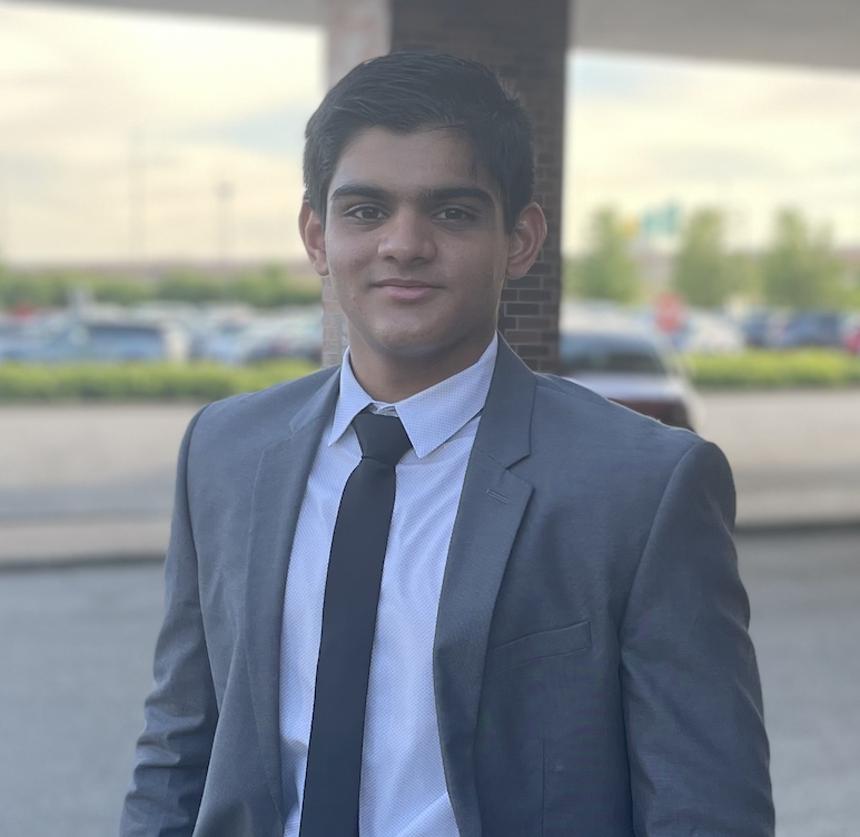 a smiling man wearing a suit jacket standing outside 