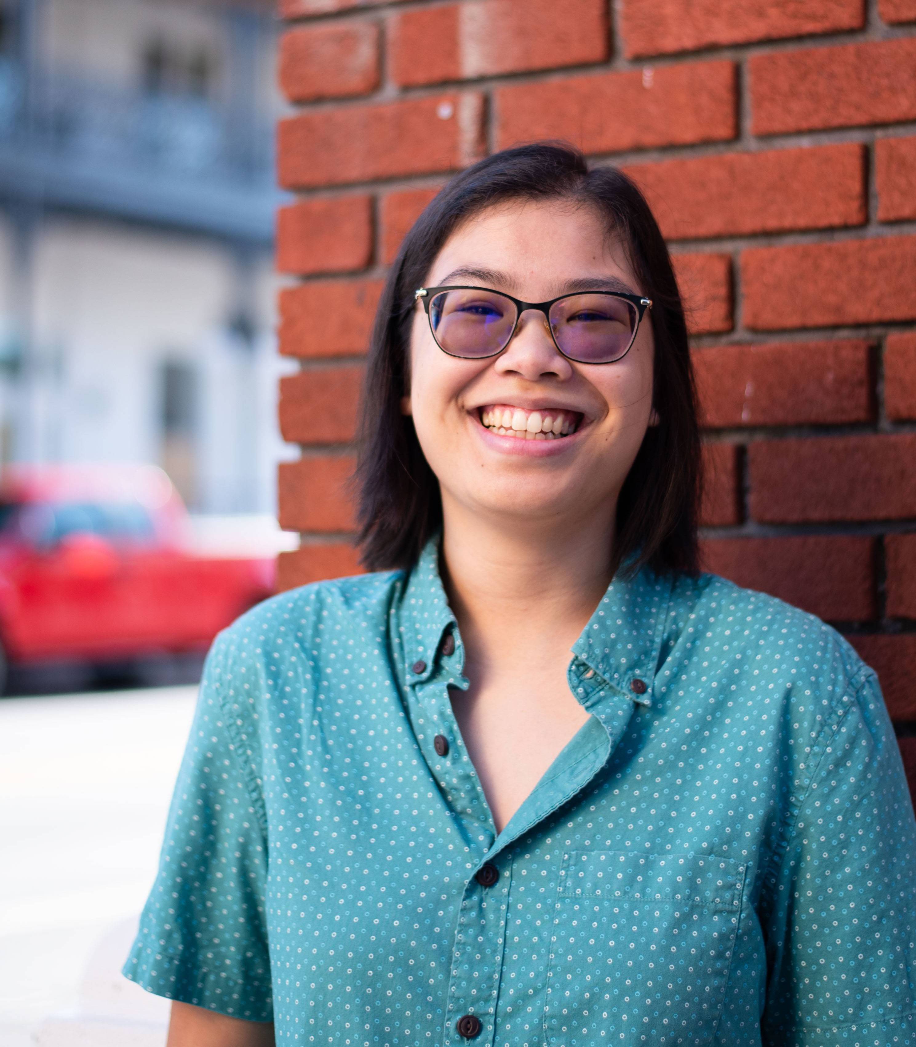 Marion Harper Person in a light blue dotted collared shirt, with shoulder length black hair and slightly tinted glasses, smiling