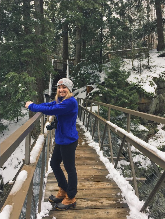 Liz Ahearn on a bridge in a forest with snow. Elizabeth Ahearn